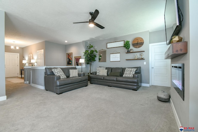 carpeted living room featuring baseboards, a ceiling fan, and a textured ceiling