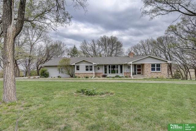 ranch-style home featuring a chimney, brick siding, and a front yard