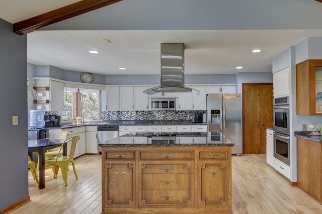 kitchen with light wood finished floors, tasteful backsplash, appliances with stainless steel finishes, and island range hood