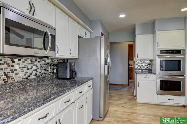 kitchen featuring light wood-style flooring, decorative backsplash, appliances with stainless steel finishes, and white cabinetry
