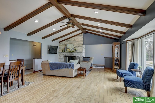 living area featuring a stone fireplace, lofted ceiling with beams, ceiling fan, light wood finished floors, and recessed lighting