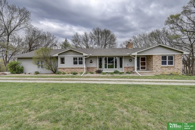 ranch-style home with brick siding, a front lawn, and a chimney