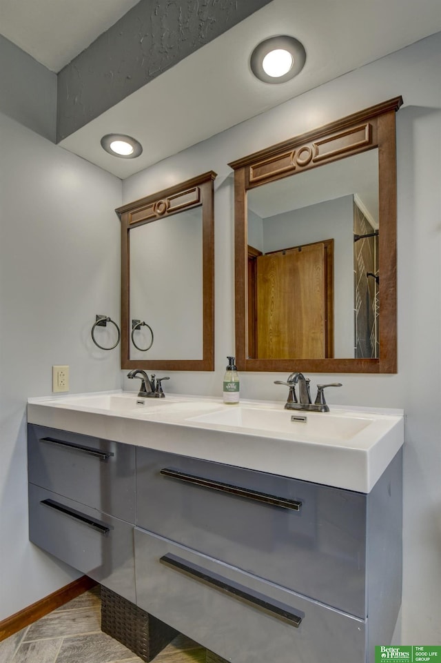 full bathroom featuring baseboards, a sink, and double vanity