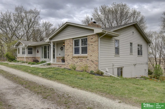 ranch-style house with a chimney, brick siding, and a front yard
