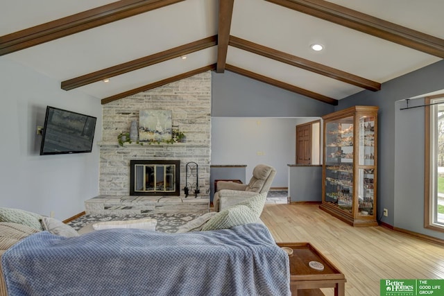 living area featuring lofted ceiling with beams, baseboards, wood finished floors, and a fireplace