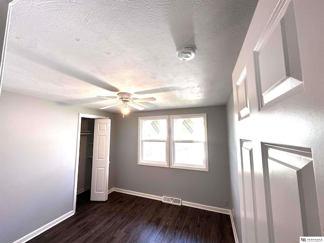 unfurnished bedroom featuring dark wood finished floors, visible vents, a closet, baseboards, and a textured ceiling