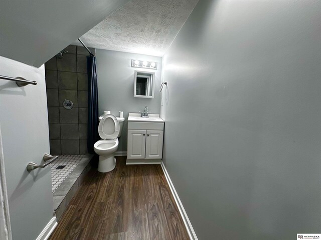 bathroom featuring a textured ceiling, toilet, a stall shower, wood finished floors, and vanity