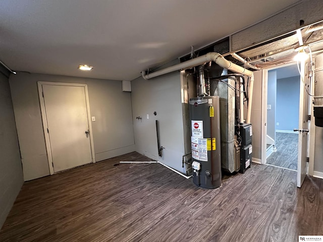 finished below grade area featuring water heater and dark wood-type flooring
