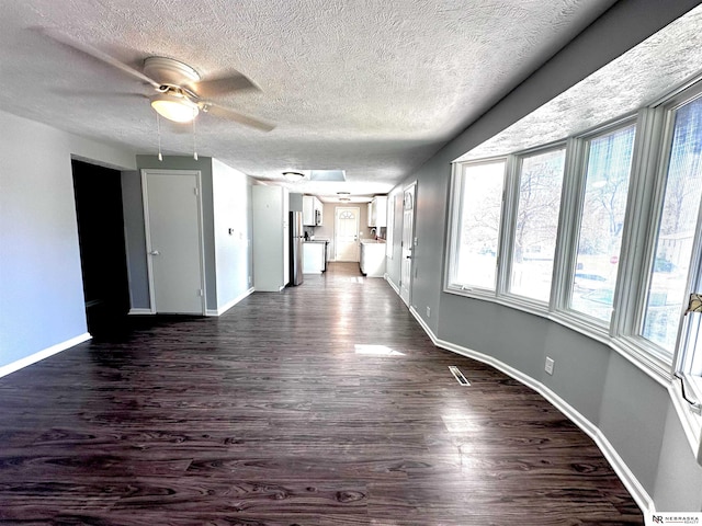 interior space featuring ceiling fan, baseboards, dark wood-type flooring, and a textured ceiling