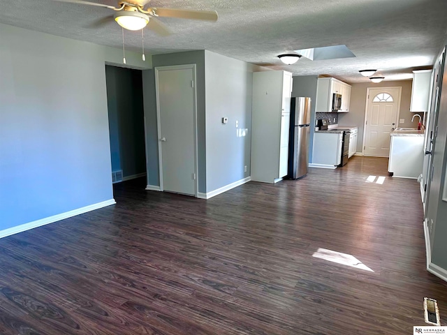 unfurnished living room featuring baseboards, a sink, dark wood-type flooring, and ceiling fan