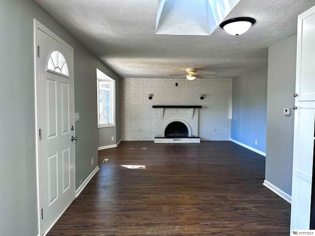 unfurnished living room with baseboards, a ceiling fan, a brick fireplace, and a textured ceiling