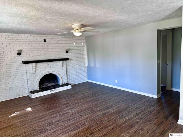 unfurnished living room featuring a textured ceiling, baseboards, wood finished floors, a brick fireplace, and ceiling fan