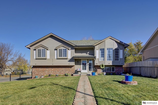 split foyer home featuring brick siding, fence, and a front yard