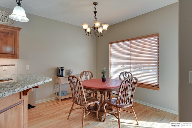 dining area featuring visible vents, light wood-style flooring, baseboards, and a notable chandelier