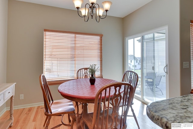 dining space featuring light wood-type flooring, baseboards, and an inviting chandelier