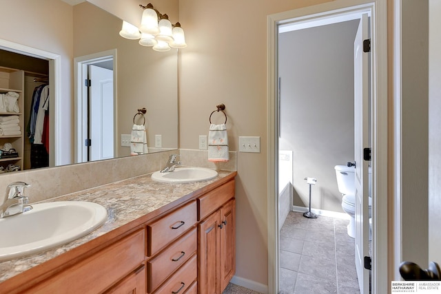 bathroom with a walk in closet, double vanity, toilet, and a sink