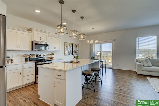 kitchen with a sink, a breakfast bar, stainless steel appliances, white cabinetry, and a kitchen island