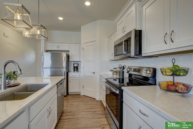 kitchen featuring white cabinetry, stainless steel appliances, light wood-type flooring, and a sink