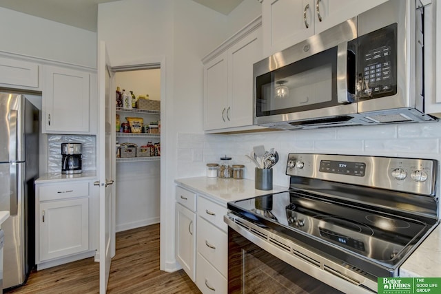 kitchen with light countertops, decorative backsplash, appliances with stainless steel finishes, and white cabinetry