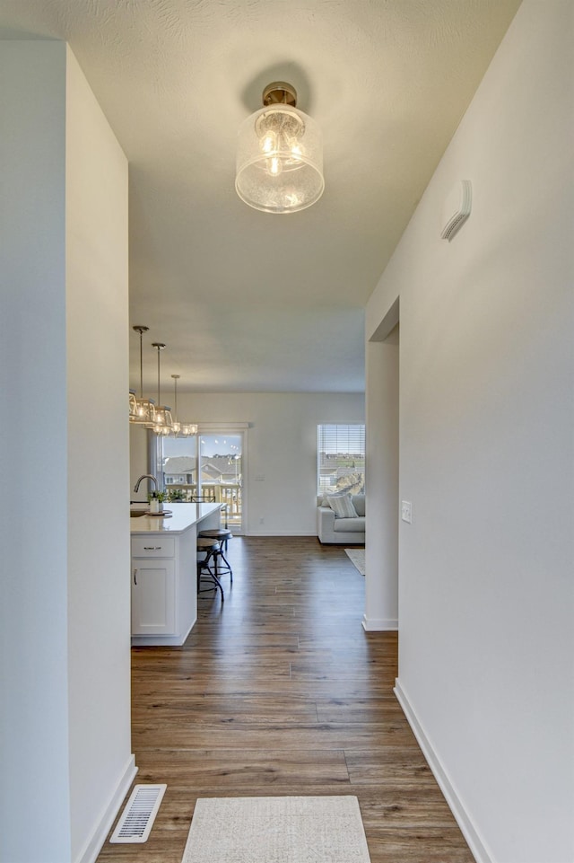 corridor featuring baseboards, dark wood-style flooring, and visible vents