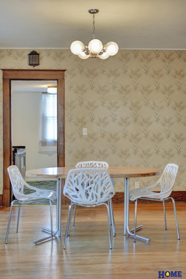 dining room featuring wallpapered walls, wood finished floors, and a notable chandelier