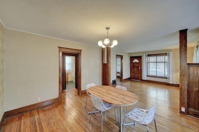 dining area with wood finished floors, ornamental molding, baseboards, and a notable chandelier
