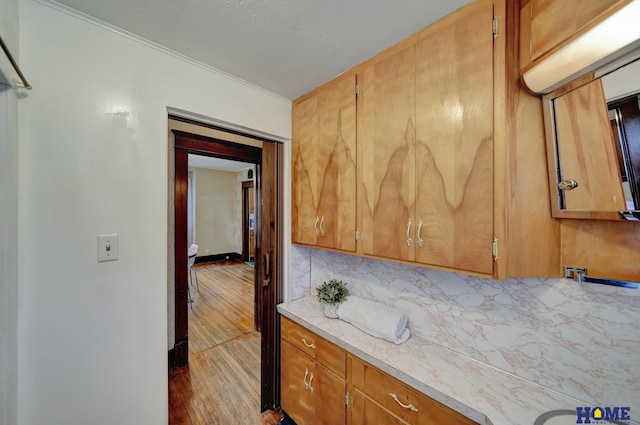 kitchen with brown cabinetry, wood finished floors, tasteful backsplash, and crown molding