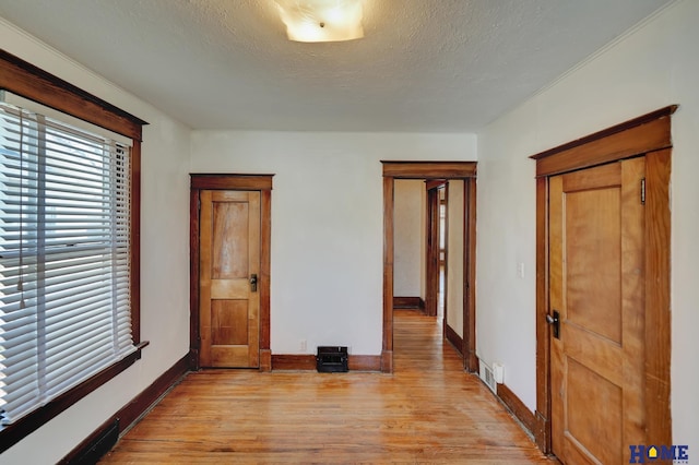 unfurnished bedroom featuring baseboards, visible vents, a textured ceiling, and light wood finished floors
