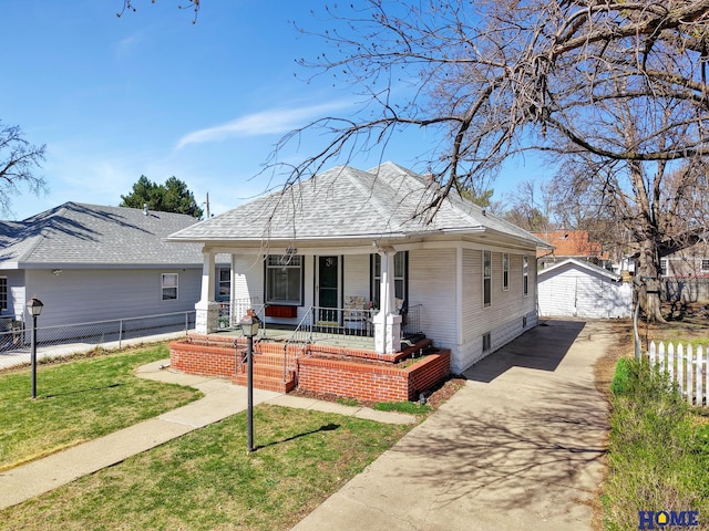 bungalow featuring a porch, driveway, an outbuilding, and fence