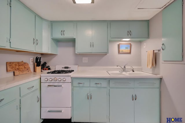 kitchen featuring white range with gas cooktop, light countertops, and a sink