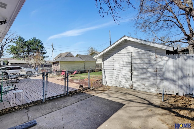 view of patio / terrace featuring a gate, a storage shed, aphalt driveway, fence, and an outbuilding