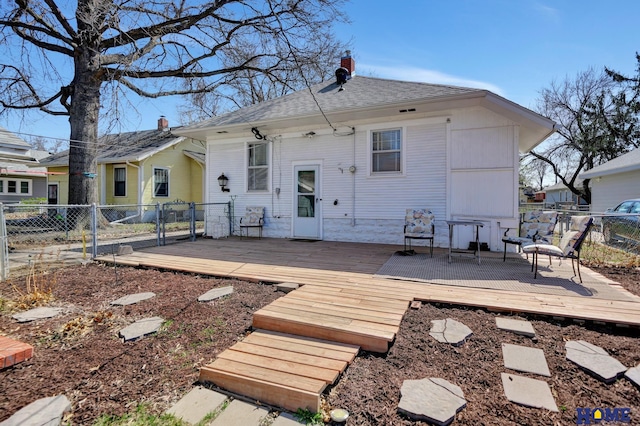 back of property with a gate, roof with shingles, fence, and a deck