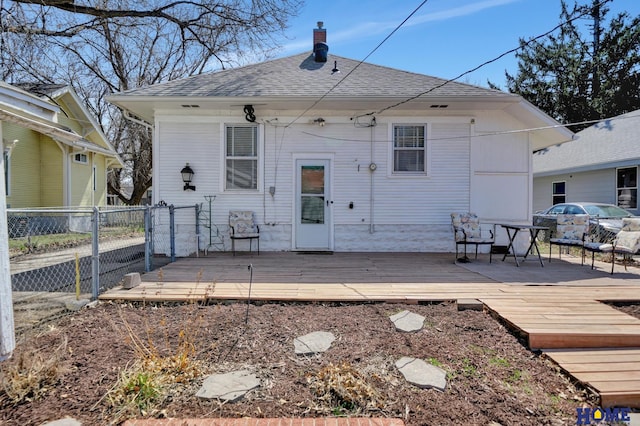 back of property featuring roof with shingles, a chimney, fence, and a deck