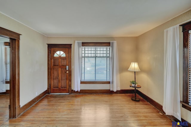 foyer entrance with light wood-type flooring, baseboards, and ornamental molding