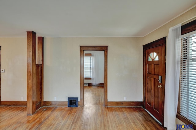 foyer entrance featuring a wealth of natural light, crown molding, wood finished floors, and baseboards