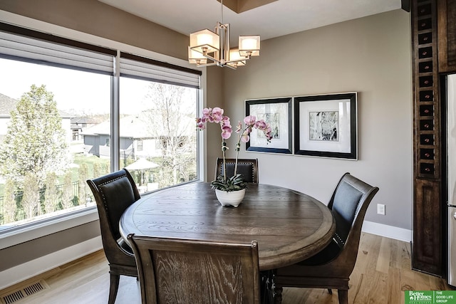 dining space with plenty of natural light, light wood finished floors, visible vents, baseboards, and a notable chandelier