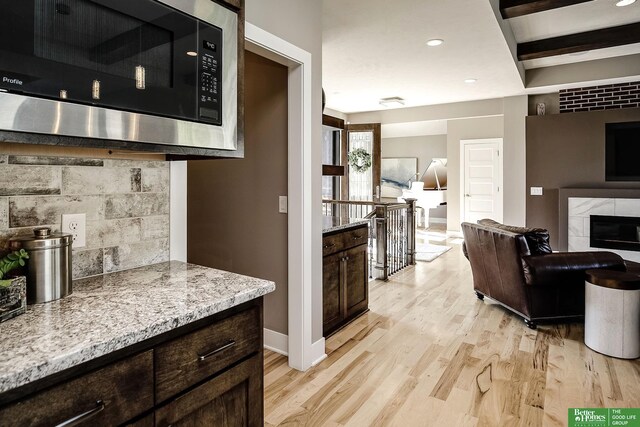 interior space featuring recessed lighting, stainless steel microwave, light wood-type flooring, baseboards, and a tiled fireplace