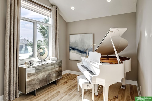 living area featuring baseboards, vaulted ceiling, and wood finished floors