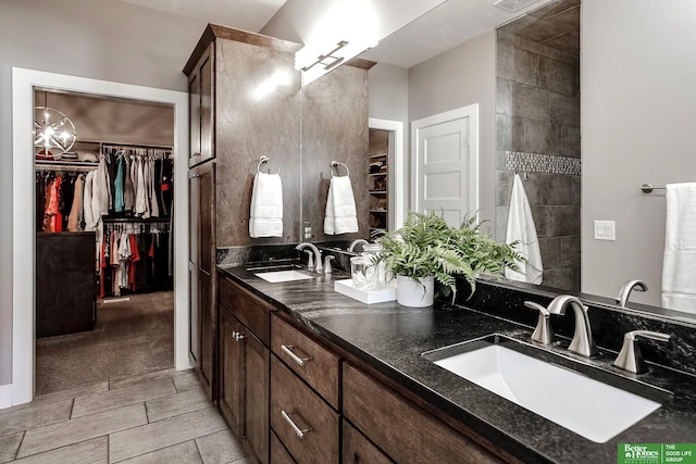 full bath featuring a walk in closet, visible vents, a sink, and double vanity
