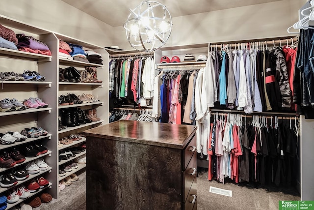 walk in closet featuring carpet floors, visible vents, and an inviting chandelier