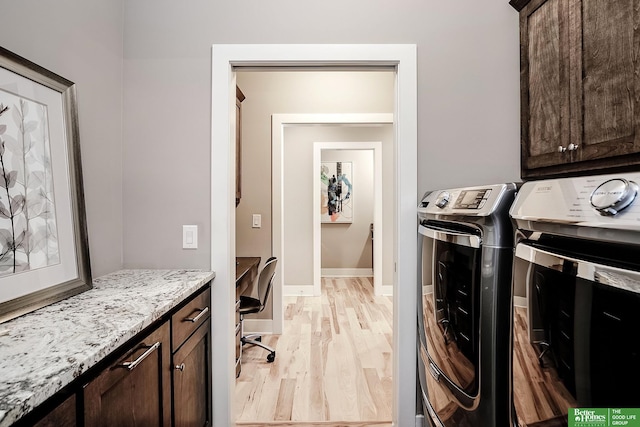 clothes washing area with baseboards, washer and dryer, light wood-style floors, and cabinet space