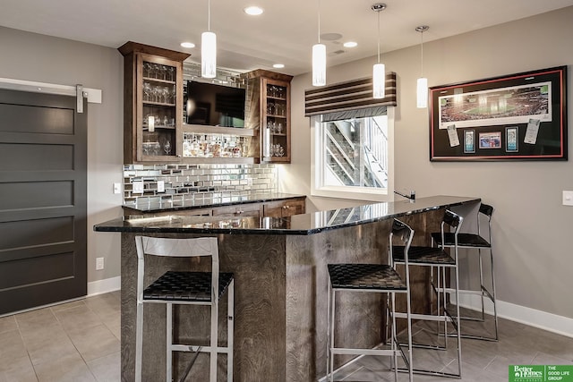 bar featuring baseboards, wet bar, tasteful backsplash, and light tile patterned floors