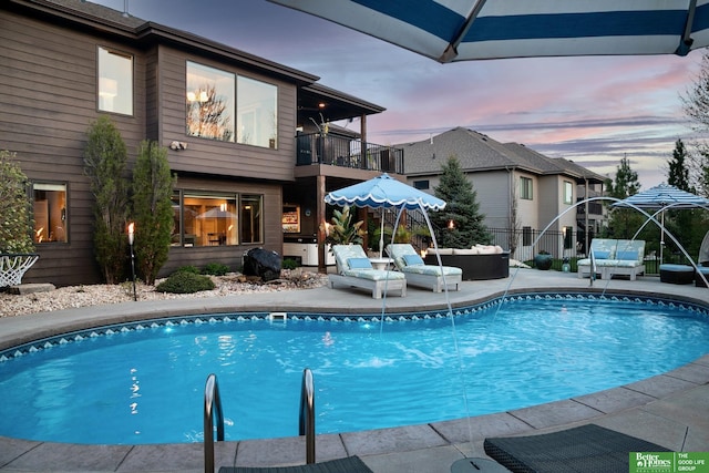 pool at dusk with a fenced in pool, a patio, fence, and an outdoor living space