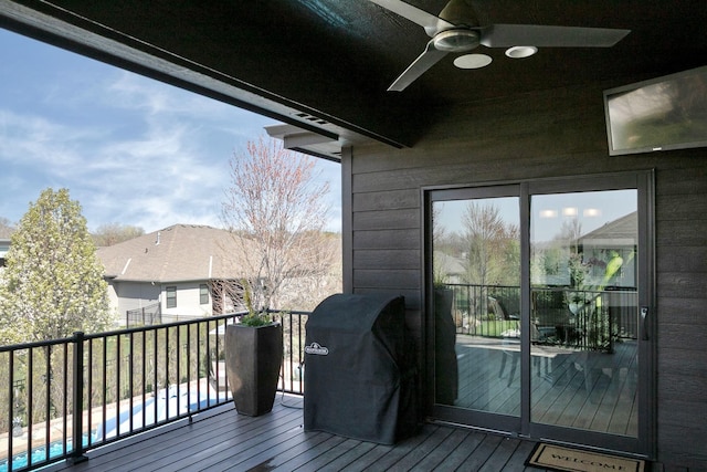 deck featuring grilling area, a ceiling fan, and a swimming pool