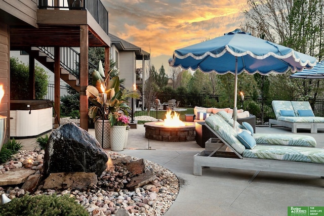 view of patio / terrace featuring fence, stairs, an outdoor living space with a fire pit, and a hot tub