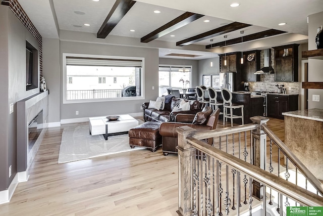 living room with recessed lighting, baseboards, a glass covered fireplace, and light wood-style flooring