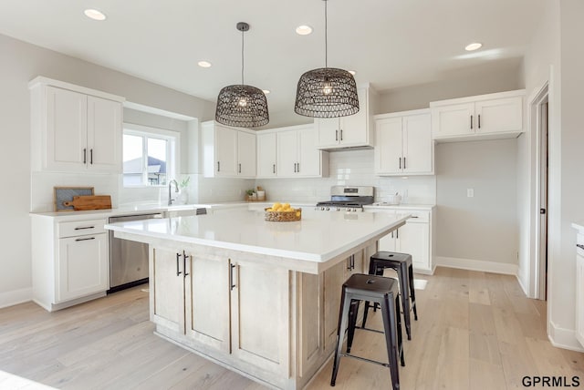 kitchen featuring tasteful backsplash, stainless steel appliances, white cabinets, a kitchen island, and recessed lighting
