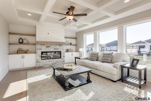 living area featuring ceiling fan, light wood-style flooring, beam ceiling, and coffered ceiling