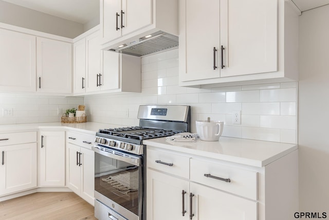kitchen featuring backsplash, white cabinetry, gas stove, and light countertops