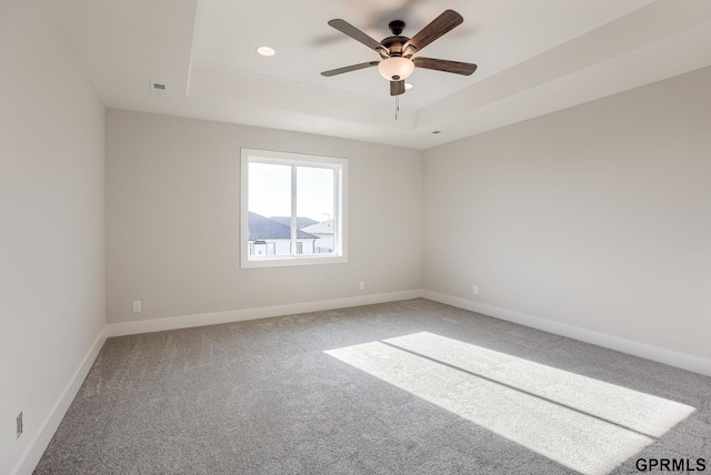 carpeted empty room with ceiling fan, a tray ceiling, baseboards, visible vents, and recessed lighting